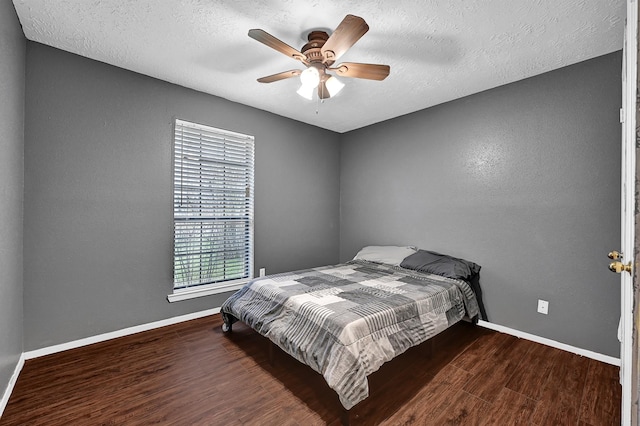 bedroom featuring a ceiling fan, wood finished floors, baseboards, and a textured ceiling