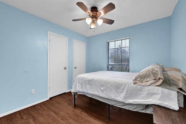 bedroom with baseboards, a ceiling fan, wood finished floors, and multiple closets