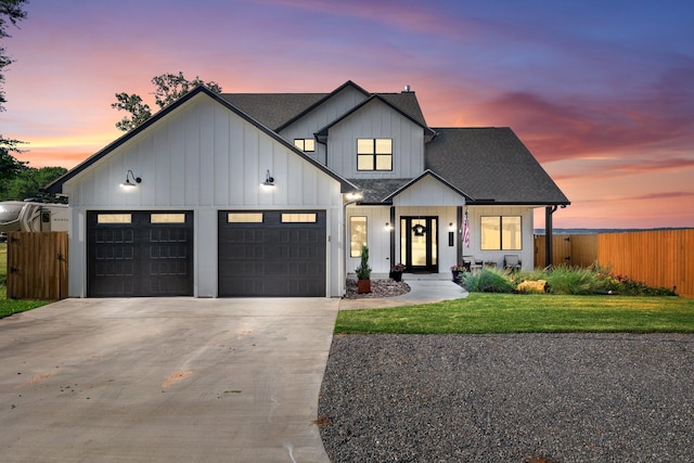 modern inspired farmhouse featuring a front lawn, fence, driveway, and a garage