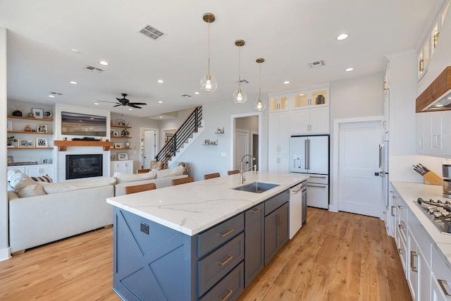 kitchen with white cabinets, a glass covered fireplace, a sink, and white appliances