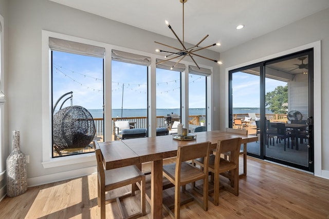 dining room with a chandelier, a water view, and light wood-style flooring
