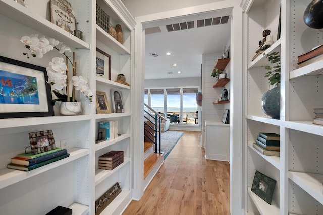 hallway featuring light wood finished floors, visible vents, and recessed lighting