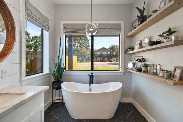 full bath featuring a soaking tub, tile patterned flooring, vanity, and plenty of natural light
