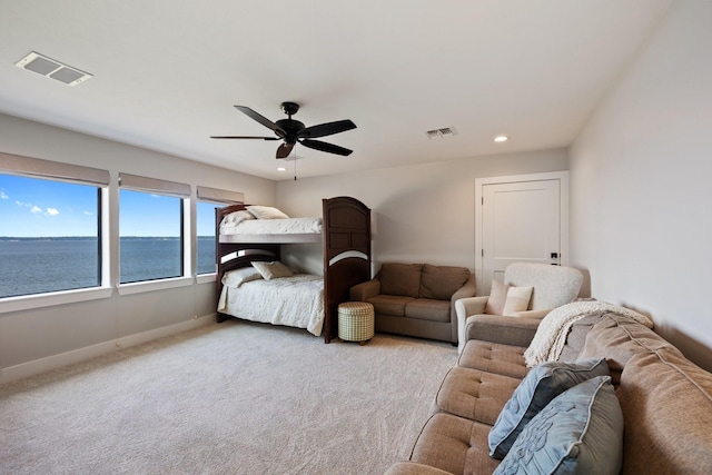 carpeted bedroom featuring recessed lighting, visible vents, baseboards, and a water view