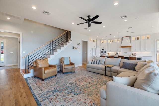 living area featuring baseboards, visible vents, recessed lighting, and stairs