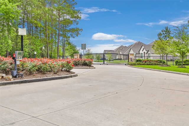 23509 Red Juniper Ln, New Caney, TX 77357 - view of concrete road with curbs, a gate, and a gated entry