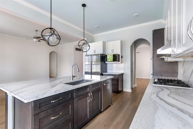23509 Red Juniper Ln, New Caney, TX 77357 - kitchen with arched walkways, appliances with stainless steel finishes, a sink, a ceiling fan, and white cabinetry