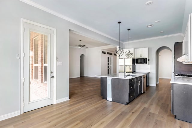 23509 Red Juniper Ln, New Caney, TX 77357 - kitchen with arched walkways, light countertops, freestanding refrigerator, a center island with sink, and baseboards