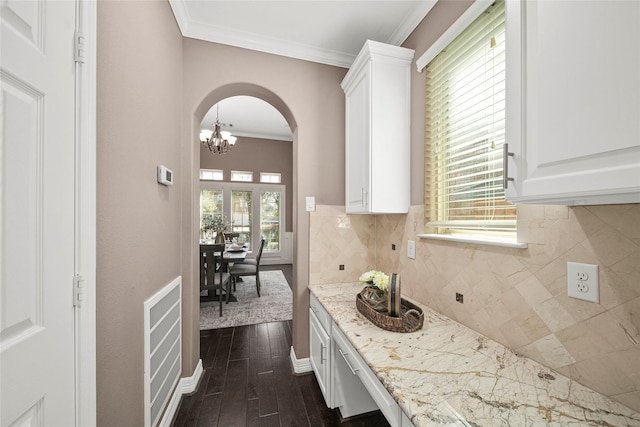 kitchen featuring arched walkways, dark wood-style flooring, ornamental molding, decorative backsplash, and white cabinetry