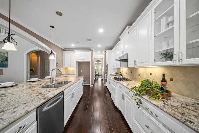 kitchen featuring light stone countertops, under cabinet range hood, stainless steel dishwasher, arched walkways, and a sink