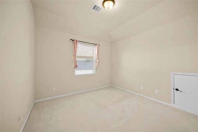 spare room featuring visible vents, light colored carpet, baseboards, and vaulted ceiling