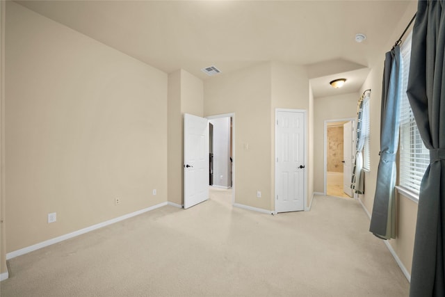 unfurnished bedroom with visible vents, baseboards, light colored carpet, and ensuite bath