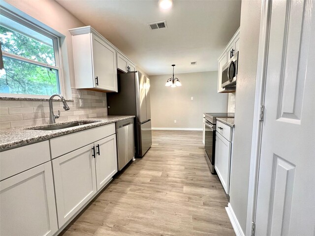 813 Cedar Lawn Dr, Alvin, TX 77511 - kitchen with decorative backsplash, appliances with stainless steel finishes, light wood-style floors, a notable chandelier, and a sink