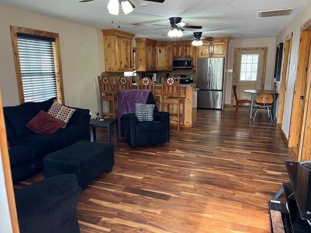 living room featuring dark wood finished floors, a ceiling fan, and visible vents