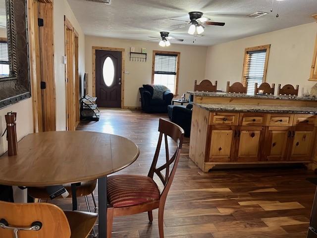interior space with dark wood-style floors, plenty of natural light, visible vents, and ceiling fan