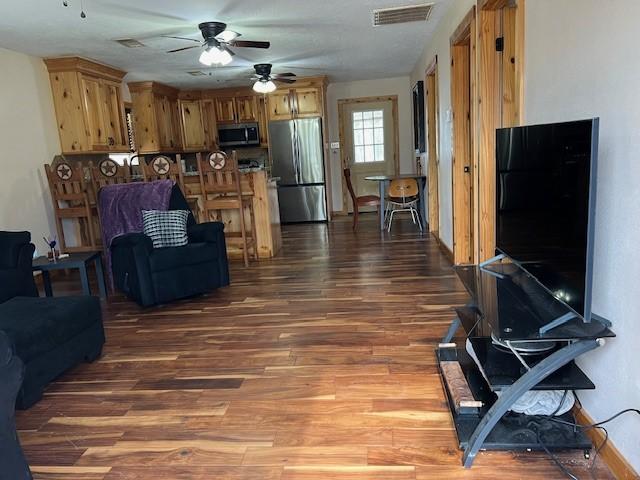 living area with visible vents, ceiling fan, and wood finished floors