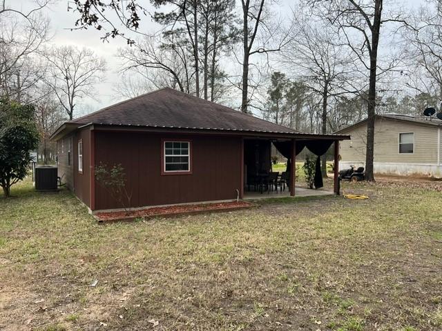 view of home's exterior with a yard, a patio area, cooling unit, and roof with shingles
