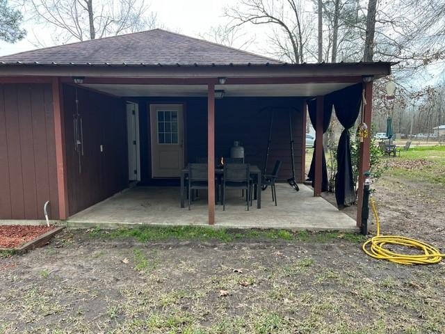 exterior space with a patio area and a shingled roof