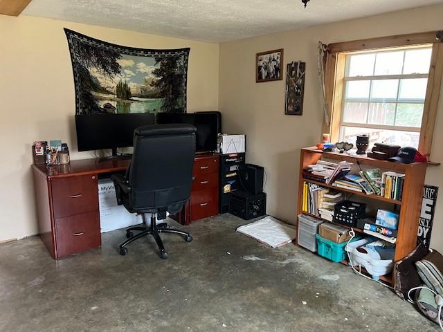 office featuring unfinished concrete floors and a textured ceiling