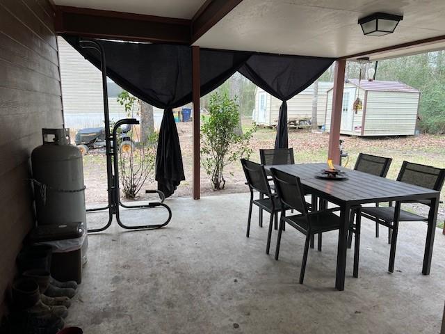 view of patio / terrace with a storage unit, outdoor dining area, and an outdoor structure