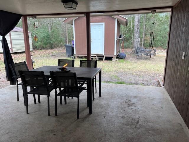 view of patio / terrace featuring outdoor dining space, a storage unit, and an outdoor structure