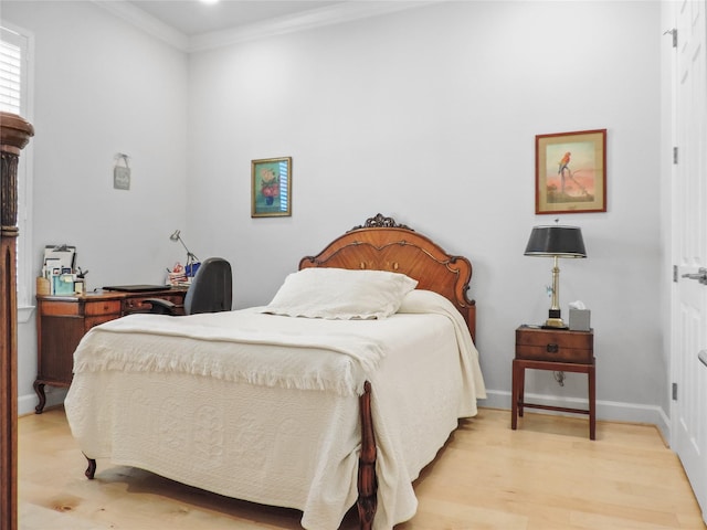 bedroom featuring light wood-type flooring, ornamental molding, and baseboards