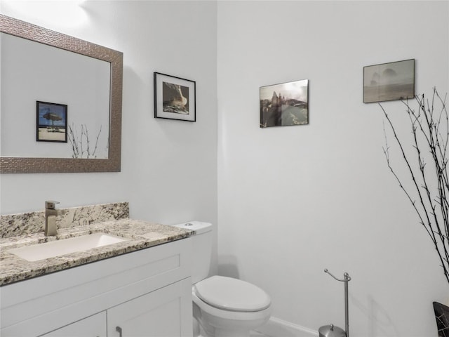bathroom featuring baseboards, toilet, and vanity