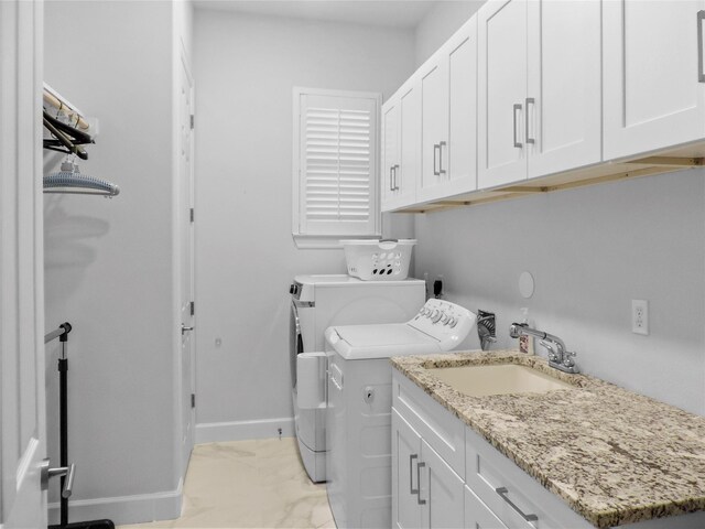 laundry room with a sink, baseboards, washer and dryer, cabinet space, and marble finish floor