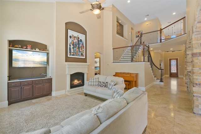 5206 Briarwick Meadow Ln, Sugar Land, TX 77479 - living room featuring a high ceiling, a warm lit fireplace, stairs, baseboards, and ceiling fan