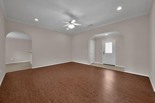 unfurnished room with wood finished floors, arched walkways, crown molding, baseboards, and ceiling fan