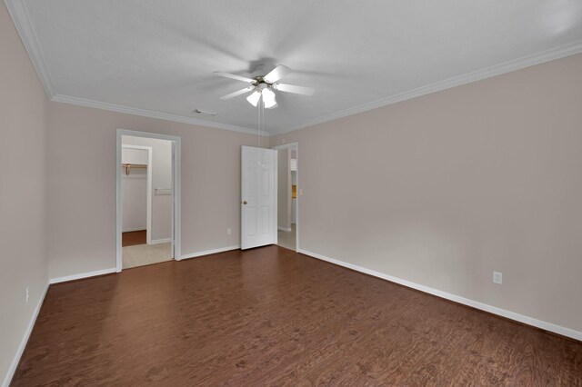 spare room with visible vents, crown molding, baseboards, ceiling fan, and dark wood-style flooring