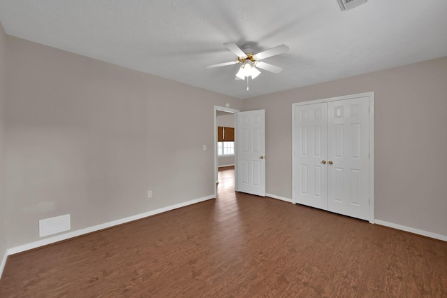 unfurnished bedroom featuring a closet, visible vents, dark wood-type flooring, and baseboards
