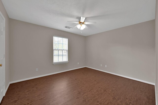 spare room featuring dark wood-type flooring, baseboards, visible vents, and ceiling fan