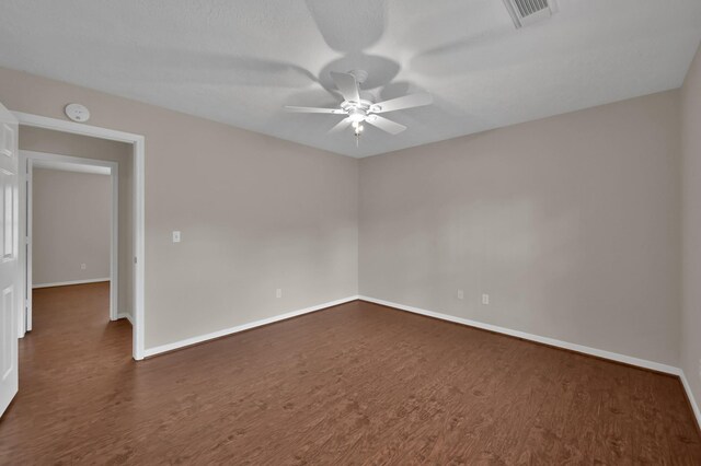 unfurnished room with visible vents, baseboards, ceiling fan, and dark wood-style flooring