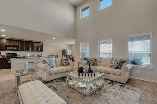 living area featuring recessed lighting, baseboards, and a high ceiling
