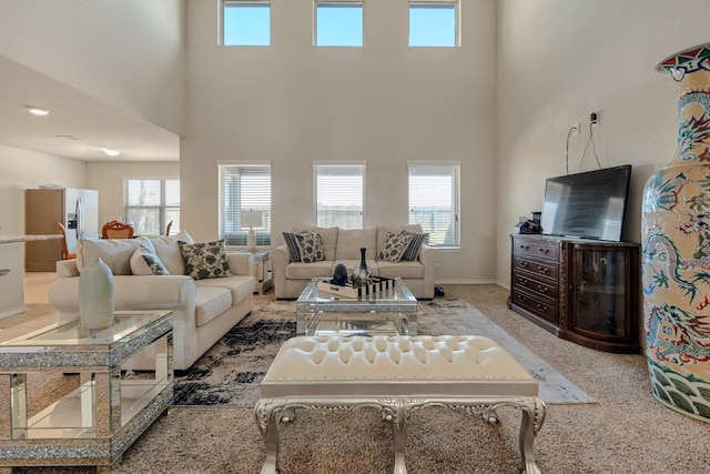 living area featuring baseboards, carpet, and a towering ceiling