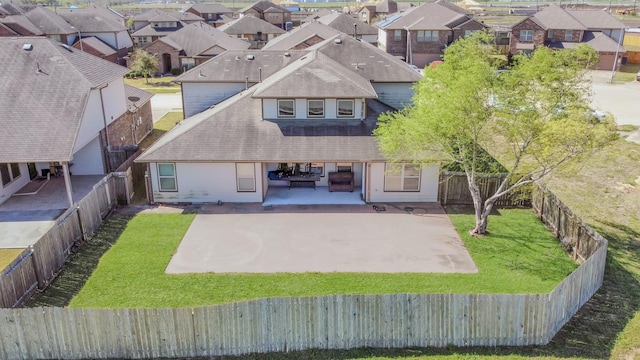 rear view of property featuring a patio, a yard, a fenced backyard, and a residential view