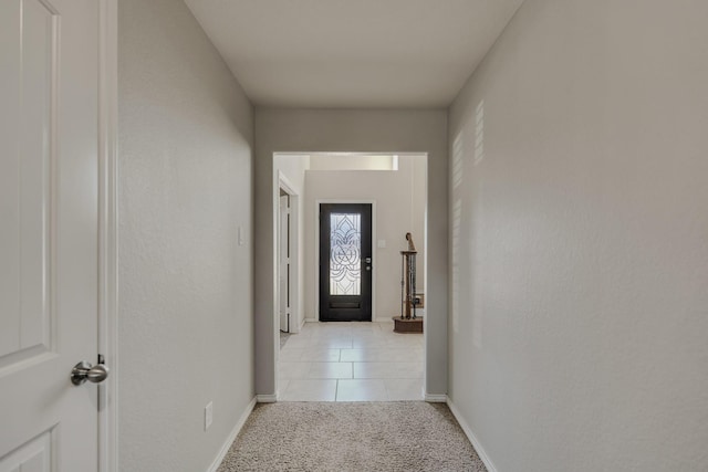 hall featuring light tile patterned floors, light colored carpet, and baseboards