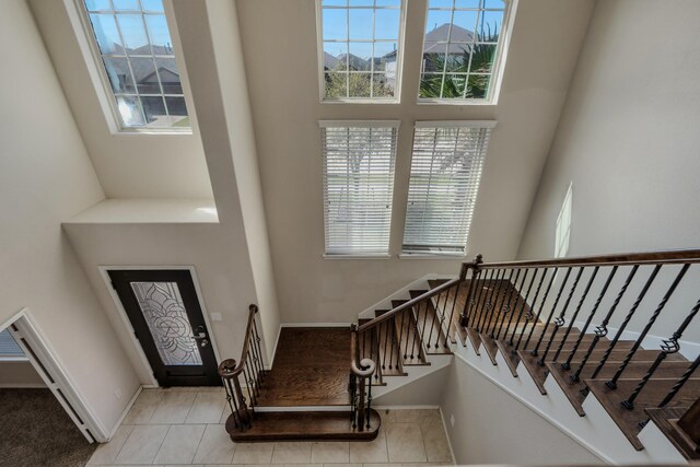 stairs featuring tile patterned floors, baseboards, and a towering ceiling