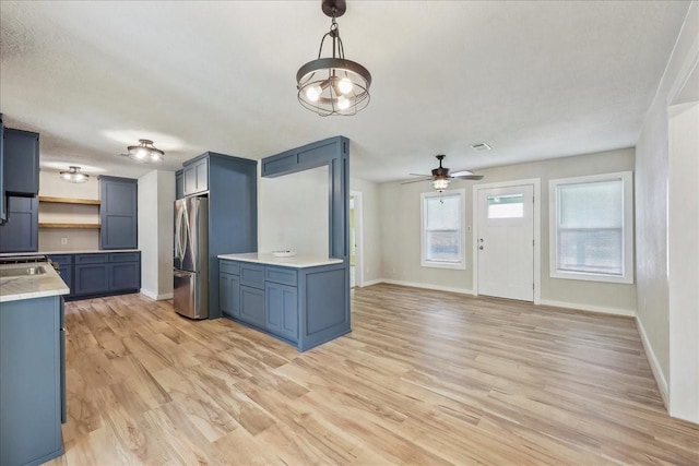 203 N 21st St, Nederland, TX 77627 - kitchen featuring freestanding refrigerator, light countertops, blue cabinets, and baseboards