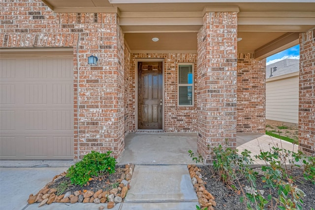 entrance to property with a garage and brick siding