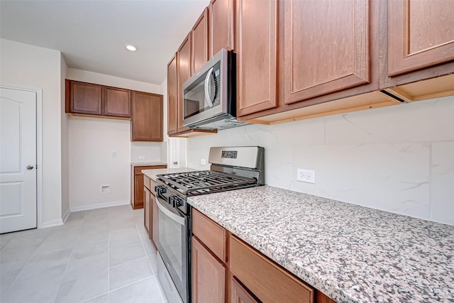 kitchen with baseboards, recessed lighting, light stone counters, appliances with stainless steel finishes, and light tile patterned floors
