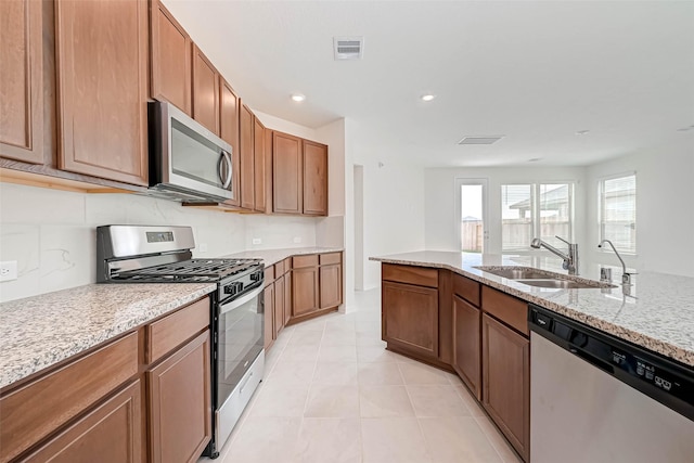 kitchen featuring visible vents, light stone countertops, a sink, light tile patterned floors, and stainless steel appliances
