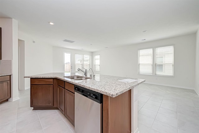 kitchen featuring light stone counters, a sink, light tile patterned floors, and dishwasher