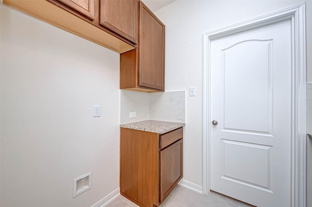 clothes washing area featuring light tile patterned flooring, baseboards, and laundry area