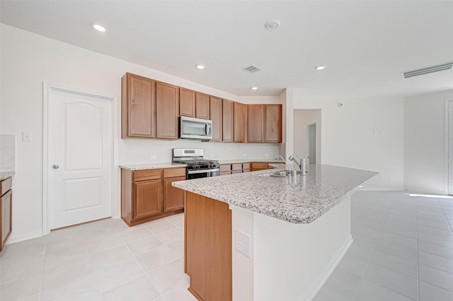 kitchen featuring a sink, appliances with stainless steel finishes, brown cabinetry, and visible vents