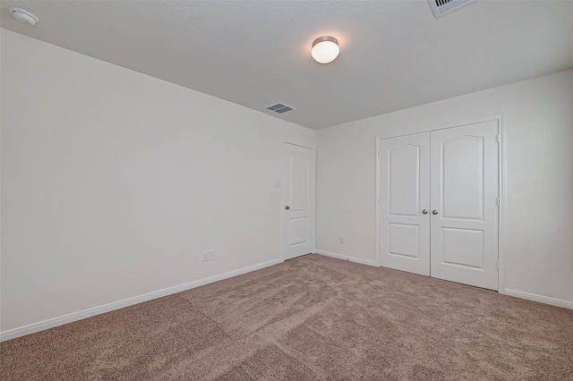 unfurnished bedroom with carpet flooring, baseboards, visible vents, and a closet