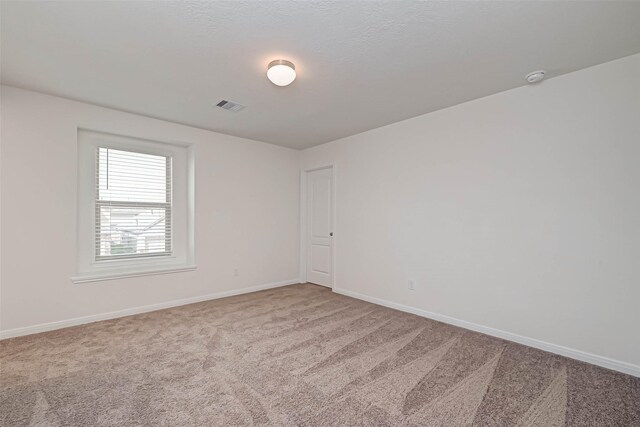 empty room featuring visible vents, baseboards, and carpet floors