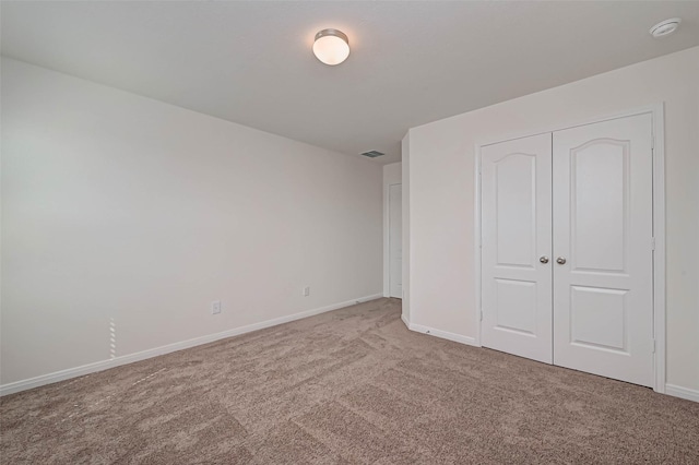 unfurnished bedroom with carpet floors, baseboards, a closet, and visible vents