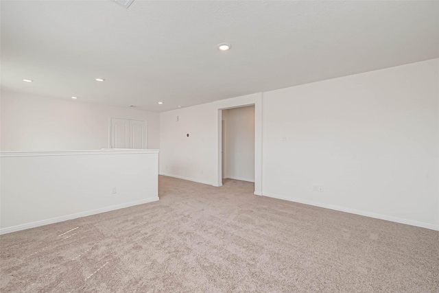 empty room with baseboards, recessed lighting, and light carpet